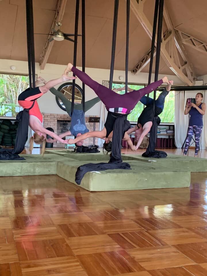 Aerial yoga practice in a beachfront pavilion