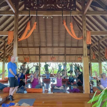 Open-air yoga class in a draped beachfront pavilion