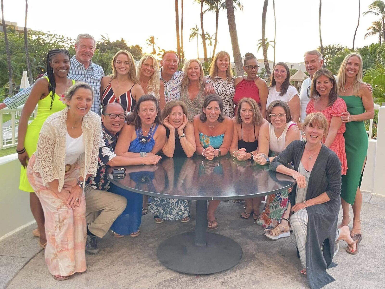 Retreat group gathered around a dinner table beneath palm trees
