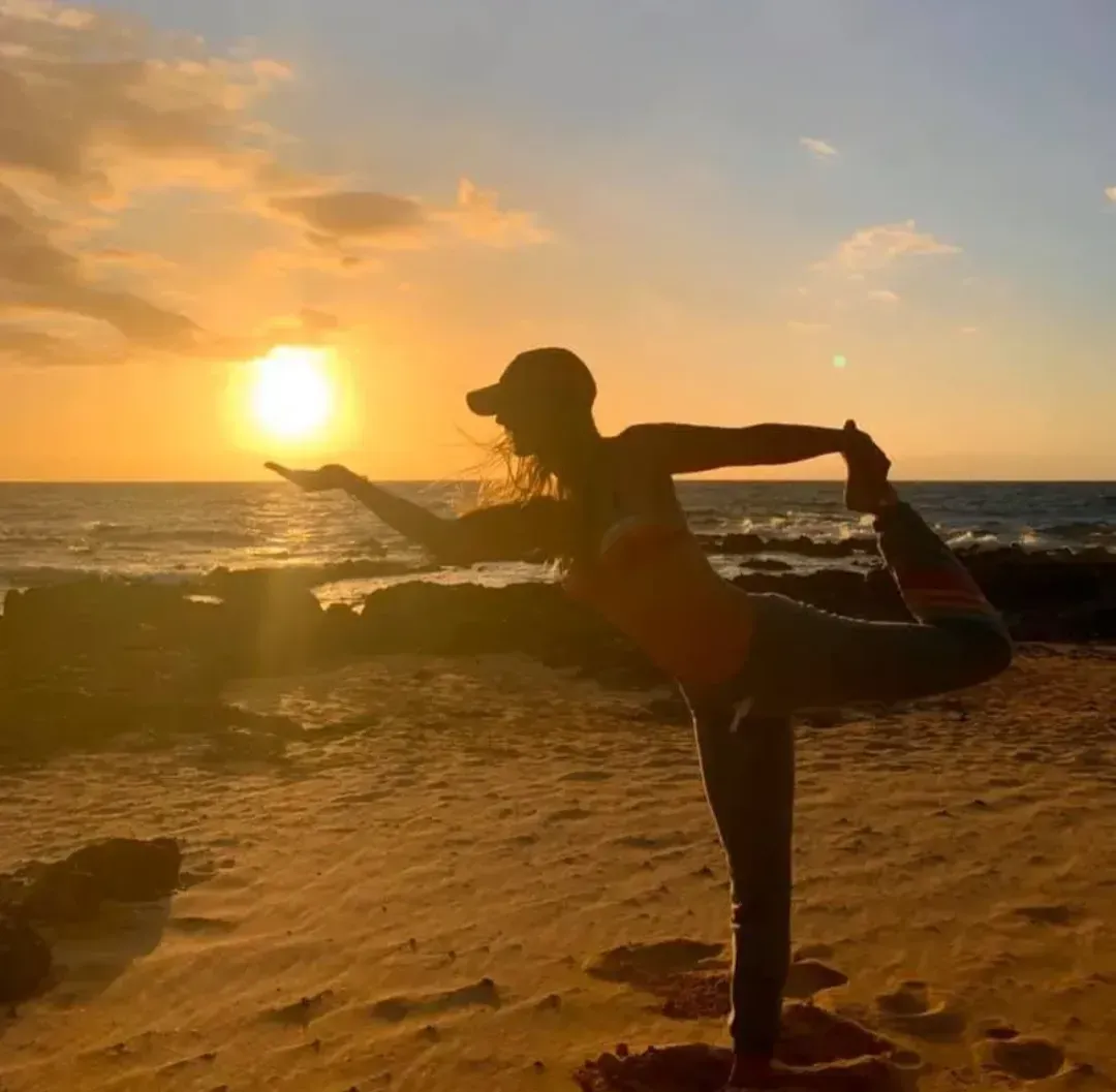 Tanya Proffitt holding a yoga pose in front of the sunset.